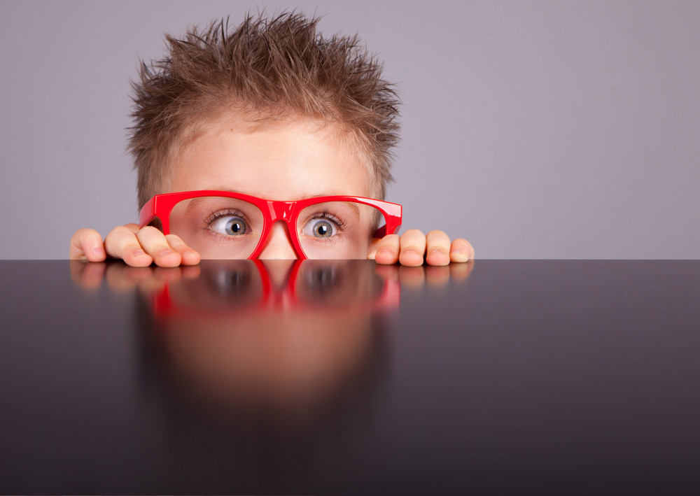 Five years old little cute boy hiding behind a table